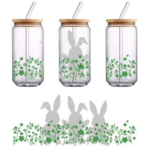 Tres conejos juguetones con motivos florales se encuentran entre tréboles verdes, creando una encantadora escena primaveral.Transferencias UV