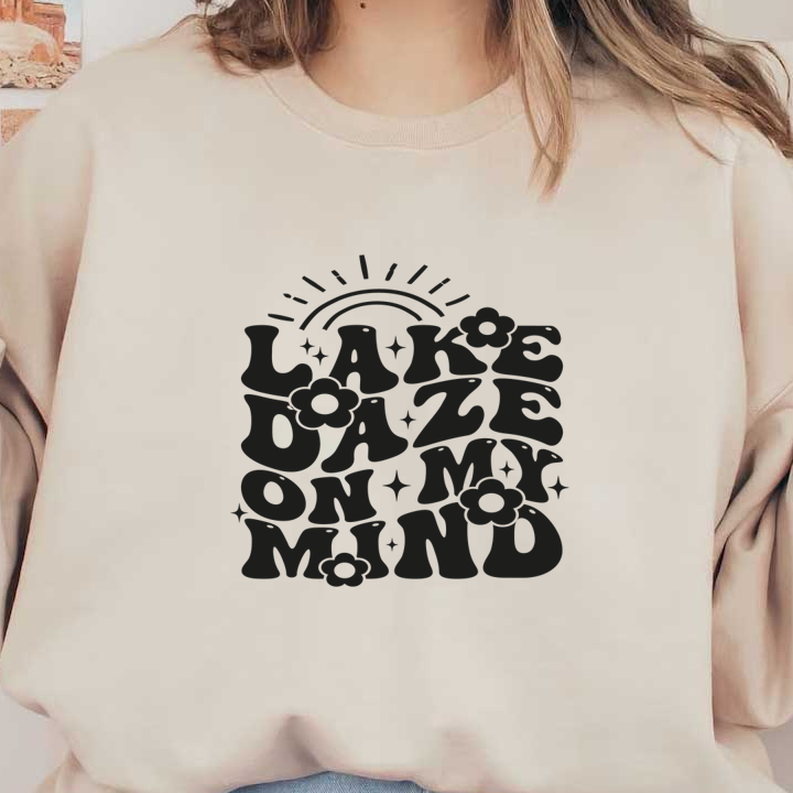 Un diseño gráfico divertido que presenta la frase "Lake Daze on My Mind", rodeada de flores y elementos solares.