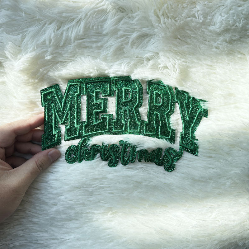 Sparkling green "MERRY CHRISTMAS" sign made from glittery material, perfect for adding a festive touch to your holiday decor.Patches