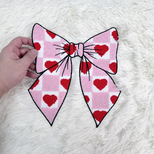 A playful pink bow with a heart pattern, perfect for adding a cute touch to any outfit or accessory.Patches