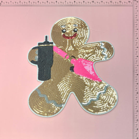 (Pre-sale Shipped within 3-5 days)A fun and sparkly gingerbread man patch adorned with sequins, holding a drink and sporting a pink accessory.Patches