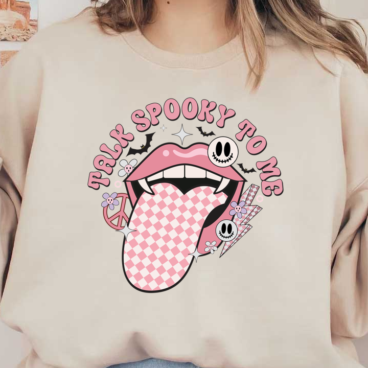 Playful graphic featuring a pink mouth with a checkered tongue, surrounded by smiley skulls and flowers, saying "Talk Spooky To Me." heat press transfers