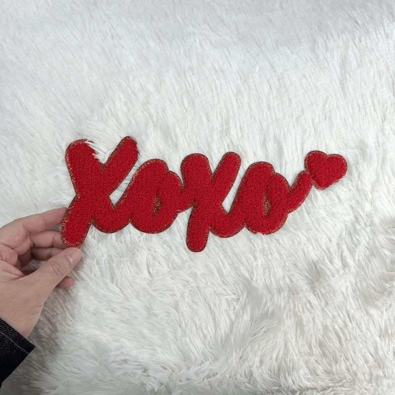 A vibrant red "XOXO" decor piece with a playful heart accent, perfect for adding a touch of love to any space.Patches