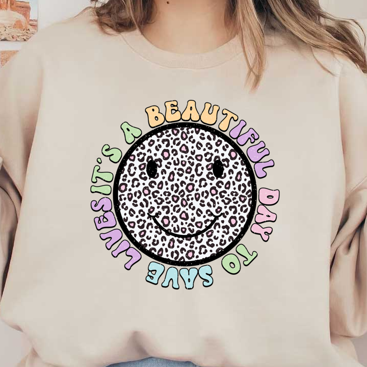 A cheerful graphic featuring a leopard print smiley face surrounded by the text "It's a beautiful day to save lives" in pastel colors.DTF Transfers