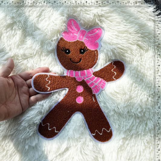 A cute plush gingerbread man with a pink bow and scarf, perfect as a festive decoration or cuddly companion.Patches