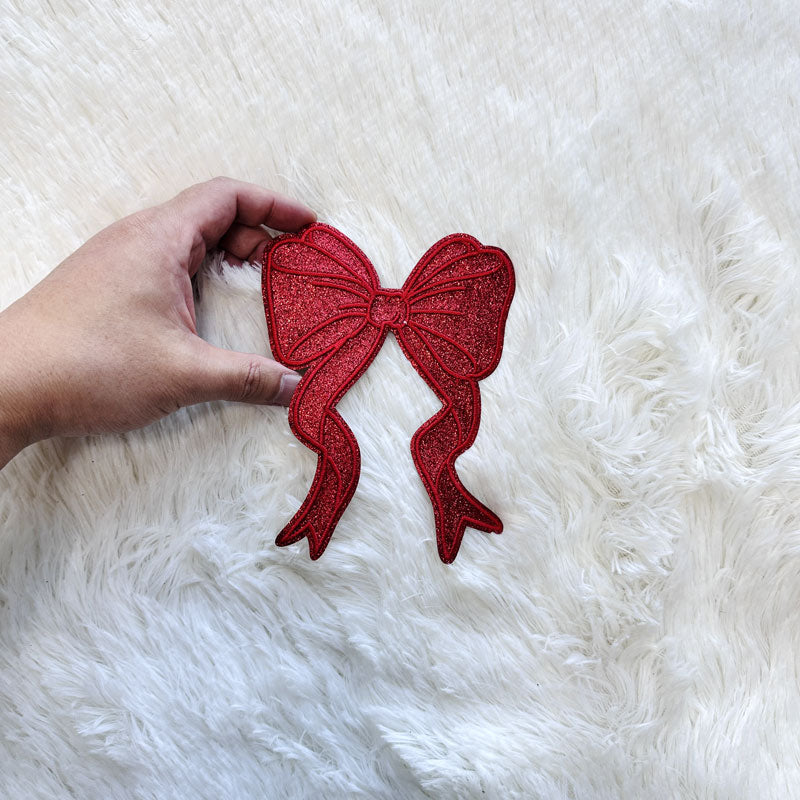 A festive Green/Red small glitter bow applique, perfect for adding a cheerful holiday touch to any garment or craft project.