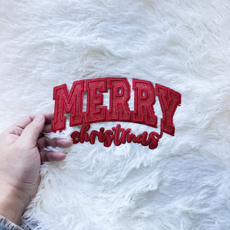 A festive Green/Red small glitter bow applique, perfect for adding a cheerful holiday touch to any garment or craft project.