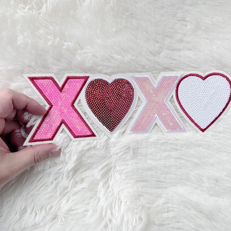 Sparkly ‘XOXO’ patch with rhinestone detailing in pink, red, and white hues, perfect for Valentine’s-themed crafts or apparel.