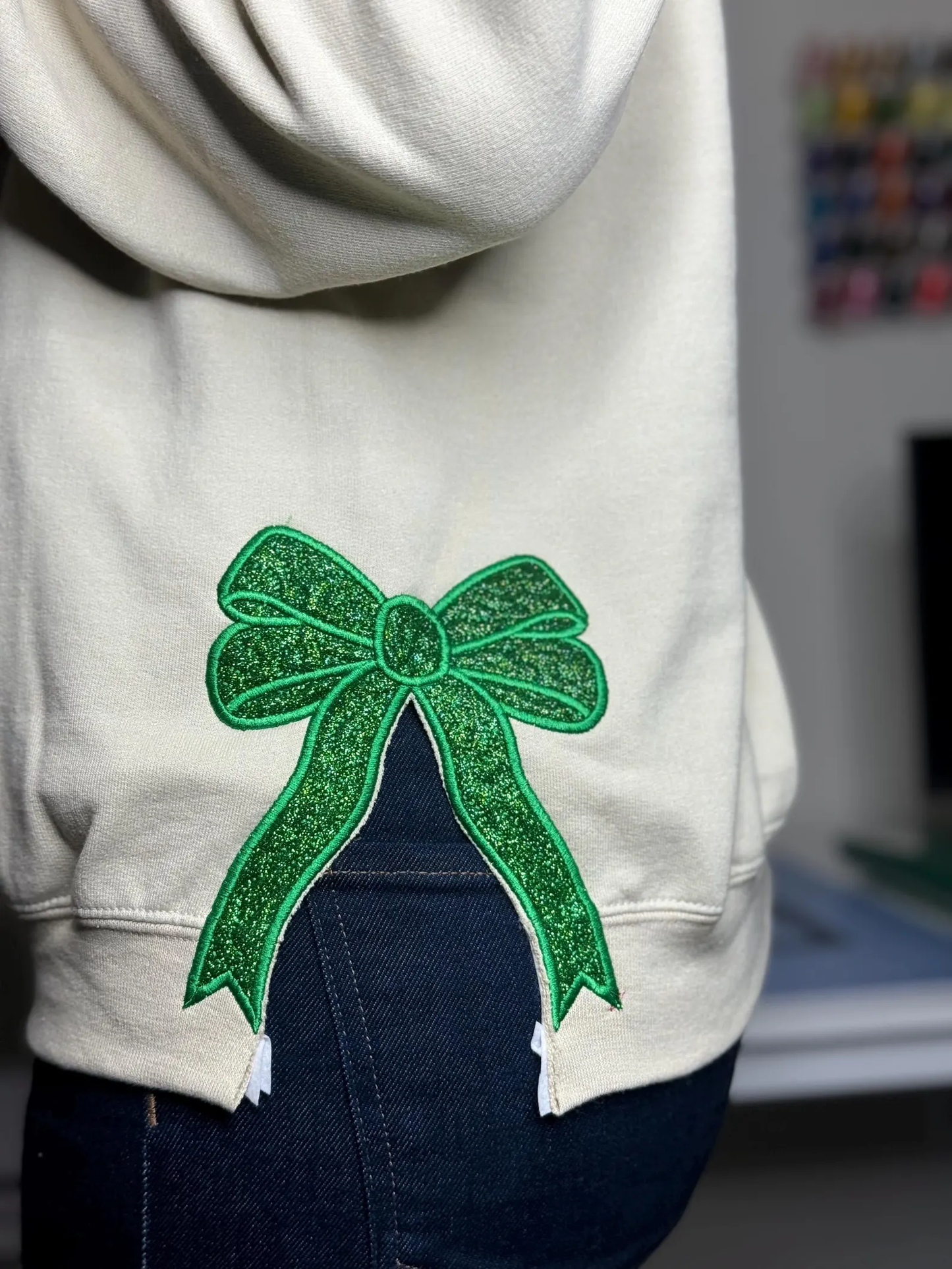 A festive Green/Red small glitter bow applique, perfect for adding a cheerful holiday touch to any garment or craft project.