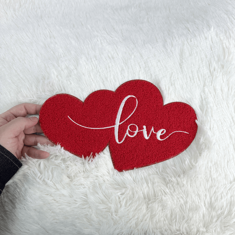 A charming red heart decoration featuring the word "love" in elegant white script, perfect for Valentine's Day or romantic décor.Patches