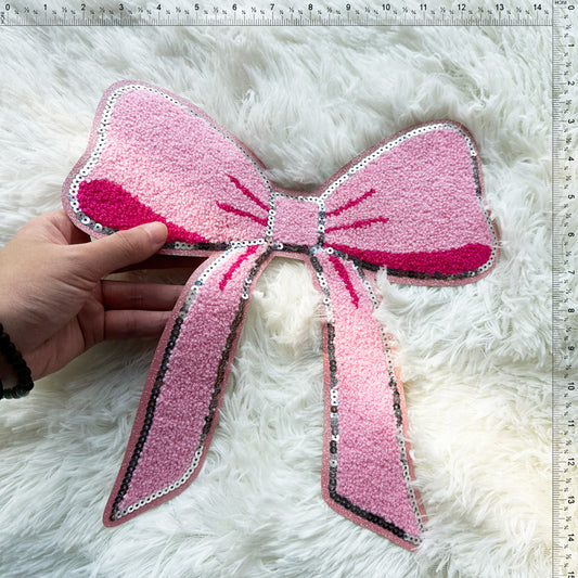 This vibrant pink bow features plush texture and sparkling sequins, making it a delightful decorative accessory.Patches