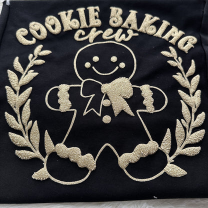 Cheerful black fabric featuring a golden embroidered gingerbread man with "Cookie Baking Crew" text, perfect for holiday baking fun!DTF Transfers puff